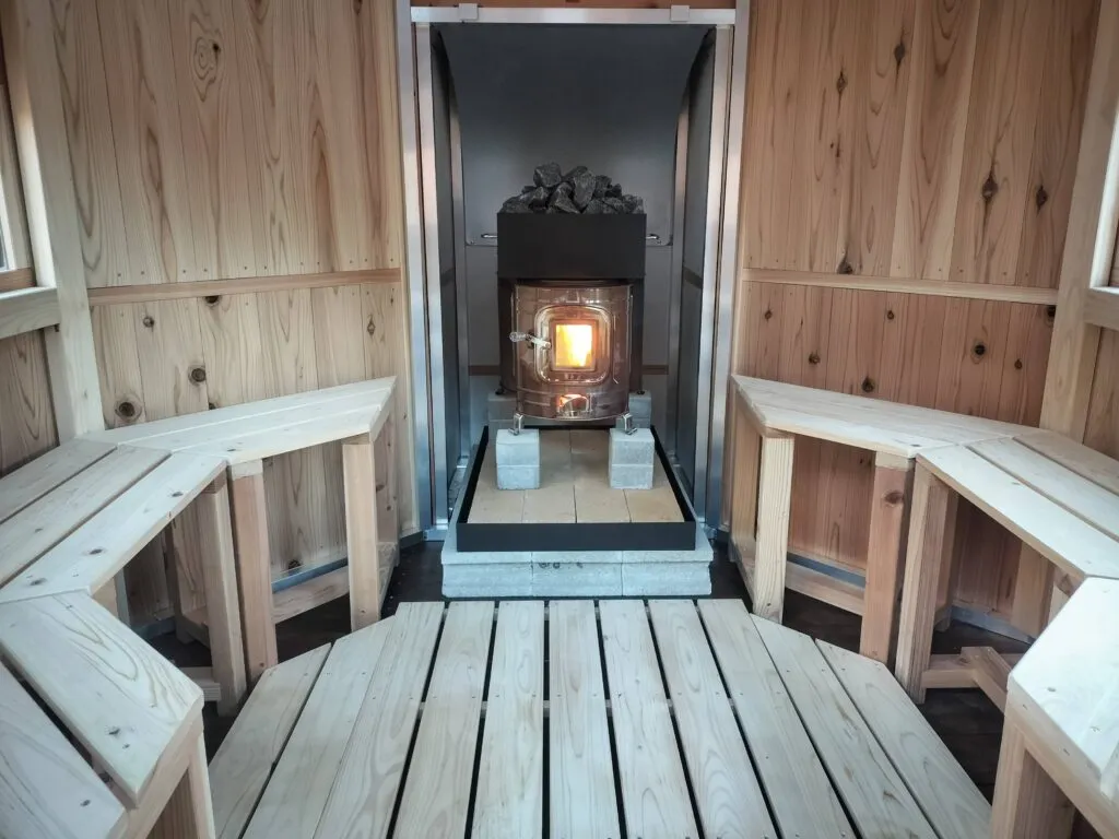 薪ストーブに火が入ったサウナ小屋の内観