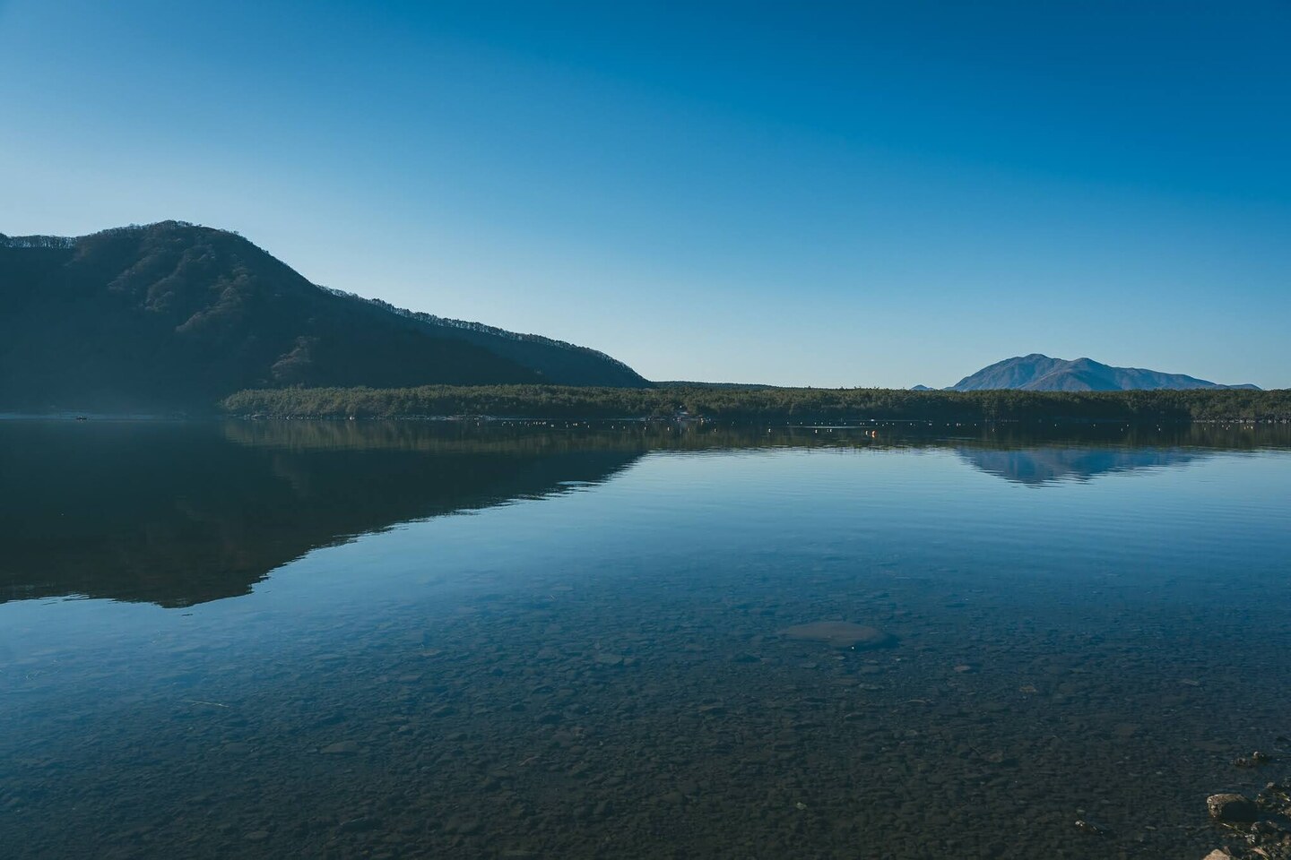 山並みと青空が穏やかな湖面に映る朝の西湖
